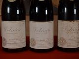 three bottles of wine are lined up on a red table
