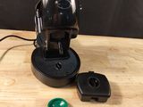 a black coffee maker with a green key on a table