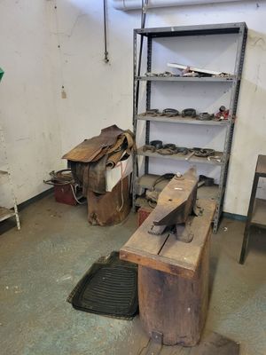 a wooden bench in the middle of a room with a shelf full of shoes
