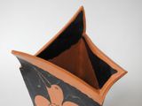 a black and orange vase sitting on a white surface