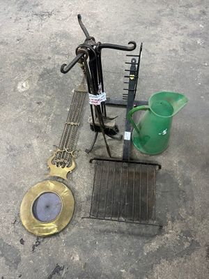 a green watering pot sitting on the ground next to a metal grate and a green watering pot