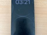 Un iPhone est posé sur une table en bois ; une horloge s'affiche à l'écran.