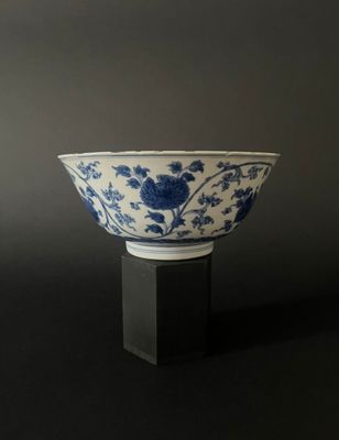 blue and white porcelain bowl on black stand against a gray background