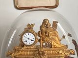 une horloge en or sous un dôme de verre sur une table