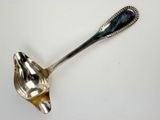 silver plated spoon with a black handle on a white surface
