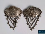 paire de boucles d'oreilles plaquées argent, ornées de chaînes et de perles sur un fond blanc