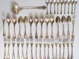 a lot of silver spoons and forks laid out on a table