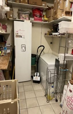 a white refrigerator in a small room with a lot of boxes on the floor
