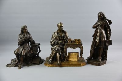 trois figurines en bronze représentant un homme et une femme assis à une table