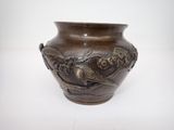 un vase marron orné d'oiseaux, posé sur une table