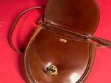a person holding a brown purse on a red surface