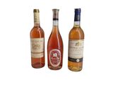 trois bouteilles de vin posées les unes à côté des autres sur une surface blanche
