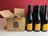six bouteilles de vin sont posées dans un carton, à côté d'un autre carton