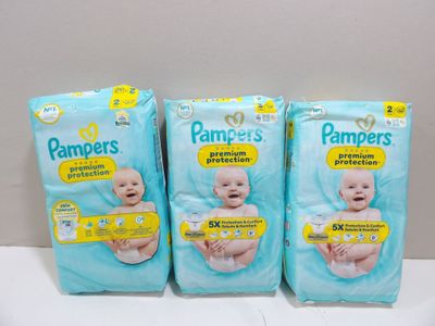 three packs of baby diapers sitting on top of a table