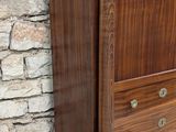 a wooden cabinet with drawers and a stone wall in the background