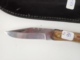 a knife that is sitting next to a leather case