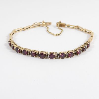 un bracelet en or orné de pierres violettes sur fond blanc