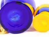 purple and yellow glass vases sitting next to each other on a white surface