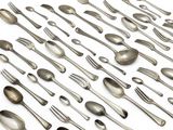 de nombreuses cuillères et fourchettes disposées ensemble sur une surface blanche