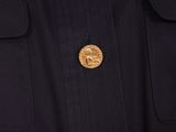 a close up of a man wearing a black jacket with a gold coin on it