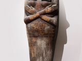 an old wooden statue of a woman with her arms crossed
