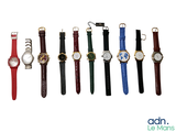 Plusieurs montres de différentes couleurs sont alignées sur une surface blanche