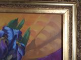 painting of a purple iris in a gold frame on a blue wall