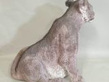 une statue représentant un chien assis sur une surface blanche