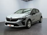 Une voiture argentée est garée dans une pièce aux murs blancs.