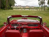 a red convertible car parked in a field with a castle in the background