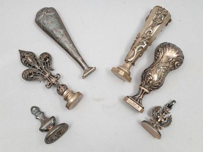 Plusieurs pièces d'argenterie ancienne sont exposées sur un support blanc