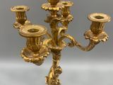 gold plated candelabra with three candles on a glass table