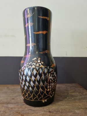 a black and gold vase sitting on a wooden table