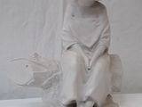 a white statue of a boy sitting on a rock