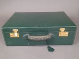a green suitcase sitting on a table with a handle
