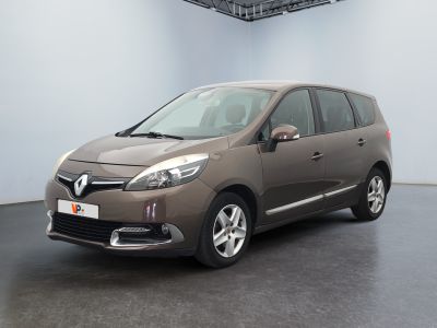La voiture marron est garée dans une grande pièce au sol noir.
