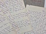 Plusieurs lettres manuscrites sont posées sur une table, à côté d'une feuille de papier