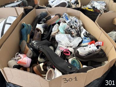 de nombreuses paires de chaussures dans une boîte en carton posée par terre