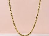 un collier à maillons dorés sur fond rose