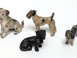 four figurines of dogs sitting on a white surface