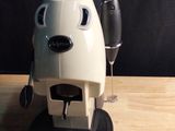 a coffee maker with two glasses of wine on the table