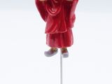 figurine of a monk in red robe on a white stand