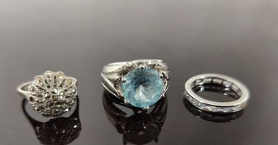trois bagues et une bague sertie d'une topaze bleue sur un fond noir