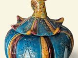 a blue and yellow vase with a bird on top of it