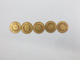 a group of five gold coins sitting on top of a white surface