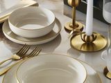 a table set with gold and white plates and silverware