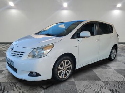 Une Toyota Sienna blanche est garée dans une pièce au sol carrelé.