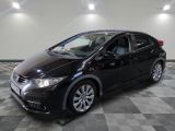 La Honda Civic noire est garée dans une salle blanche.