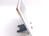 a white and gold cell phone sitting on a stand