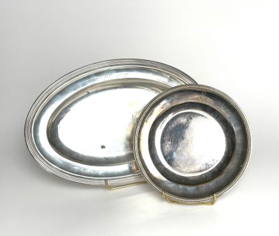 two silver plates with lids are sitting on a white surface